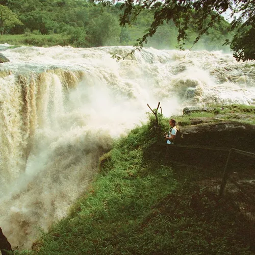 Traveller standing at the viewing platform beside the thundering Murchison Falls on the Victoria Nile in Murchison Falls National Park Uganda - Contiki Uganda Tour