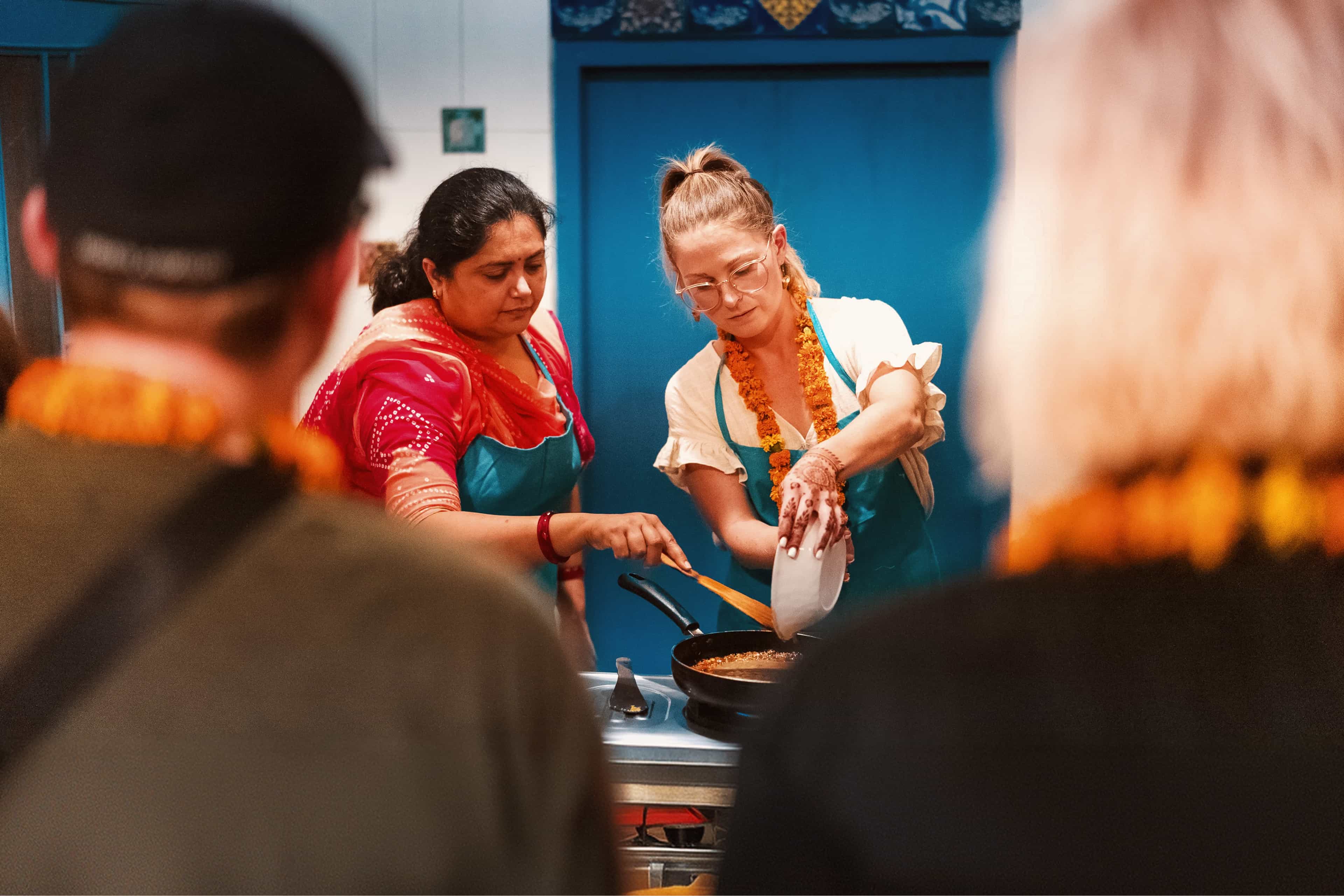Local host guiding a traveller through a home-cooked meal during a cooking class in India.