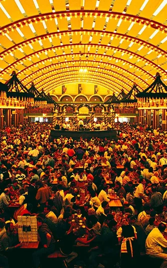 Packed Oktoberfest beer hall tent with ornate vaulted ceiling and thousands of revellers at long wooden tables in Munich Germany - Contiki Oktoberfest Tour