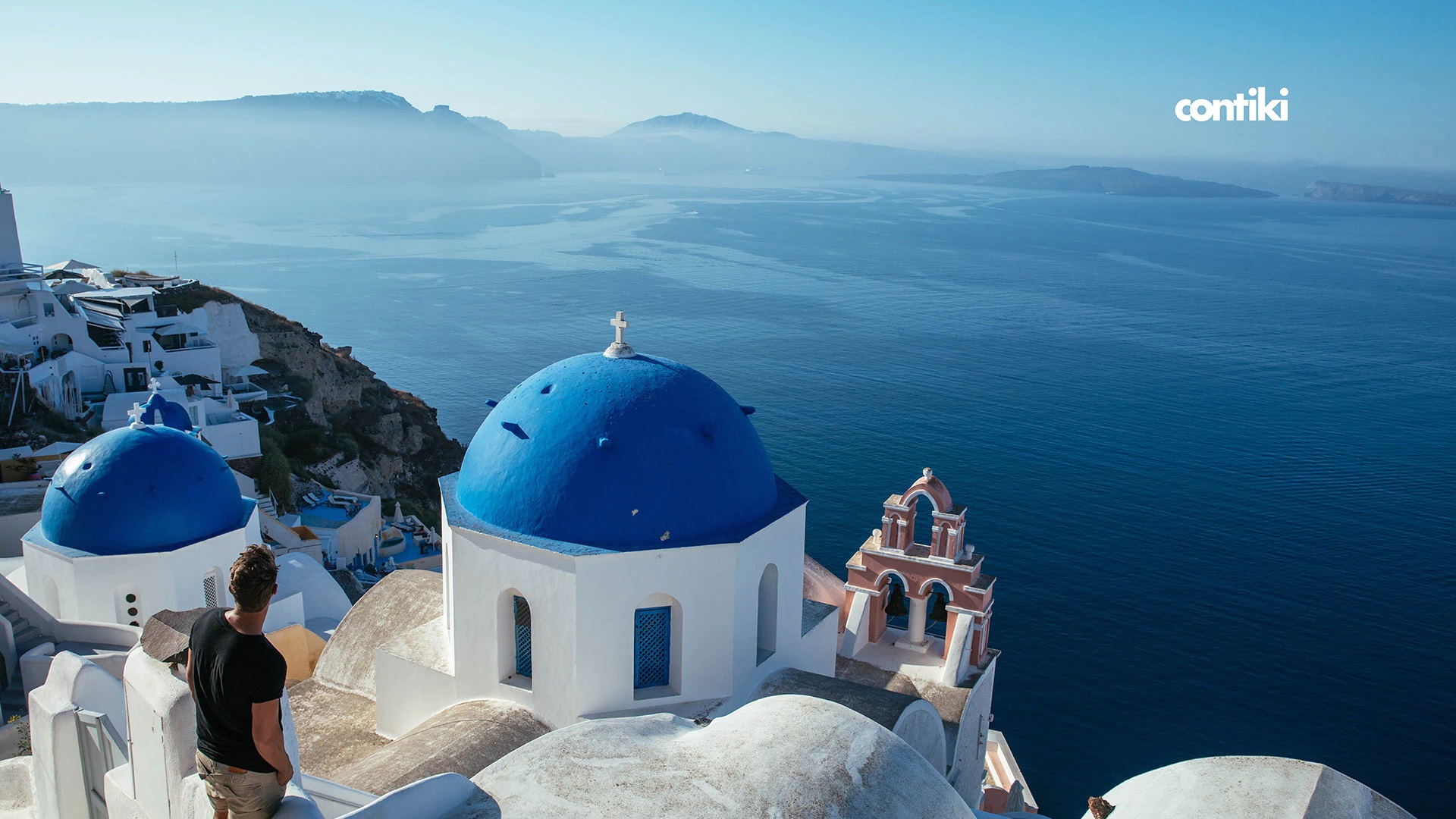 A tourist looking at the blue roofs of buildings in Santorini