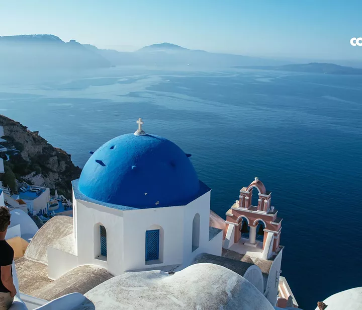 A tourist looking at the blue roofs of buildings in Santorini