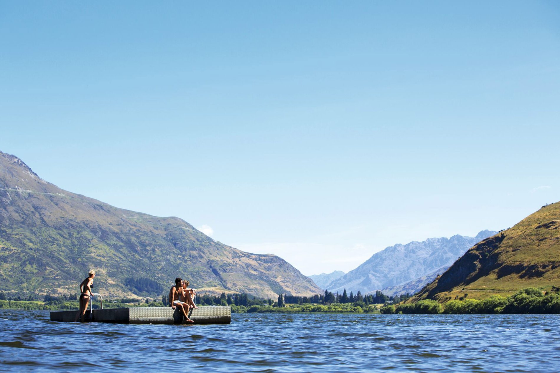 A group of people on a platform in the middle of a lake with mountains around in New Zealand.