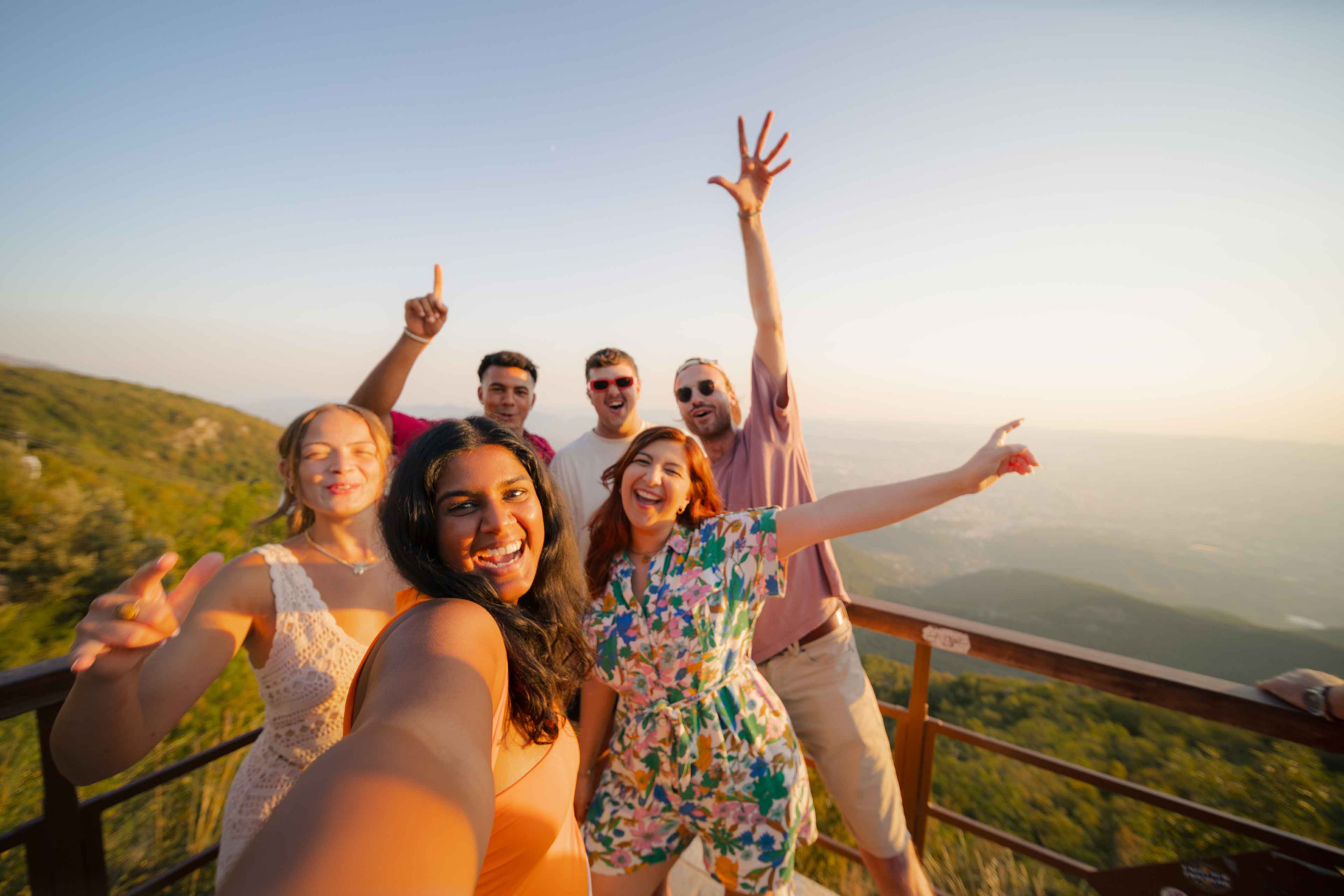 A group of friends is taking a selfie with a scenic mountain.