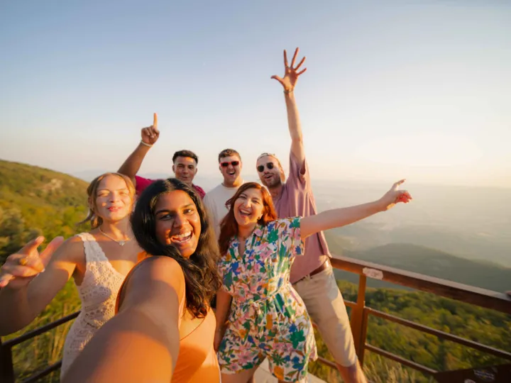 A group of friends is taking a selfie with a scenic mountain.