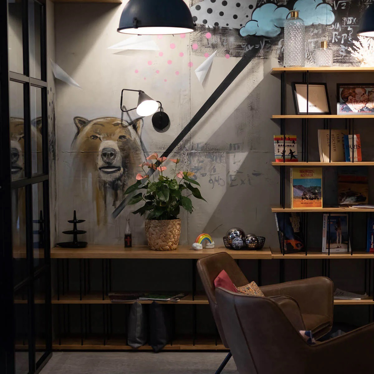 Moxy Hotel Berlin public area with armchair, bookshelf, decorations and bear painting on a wall