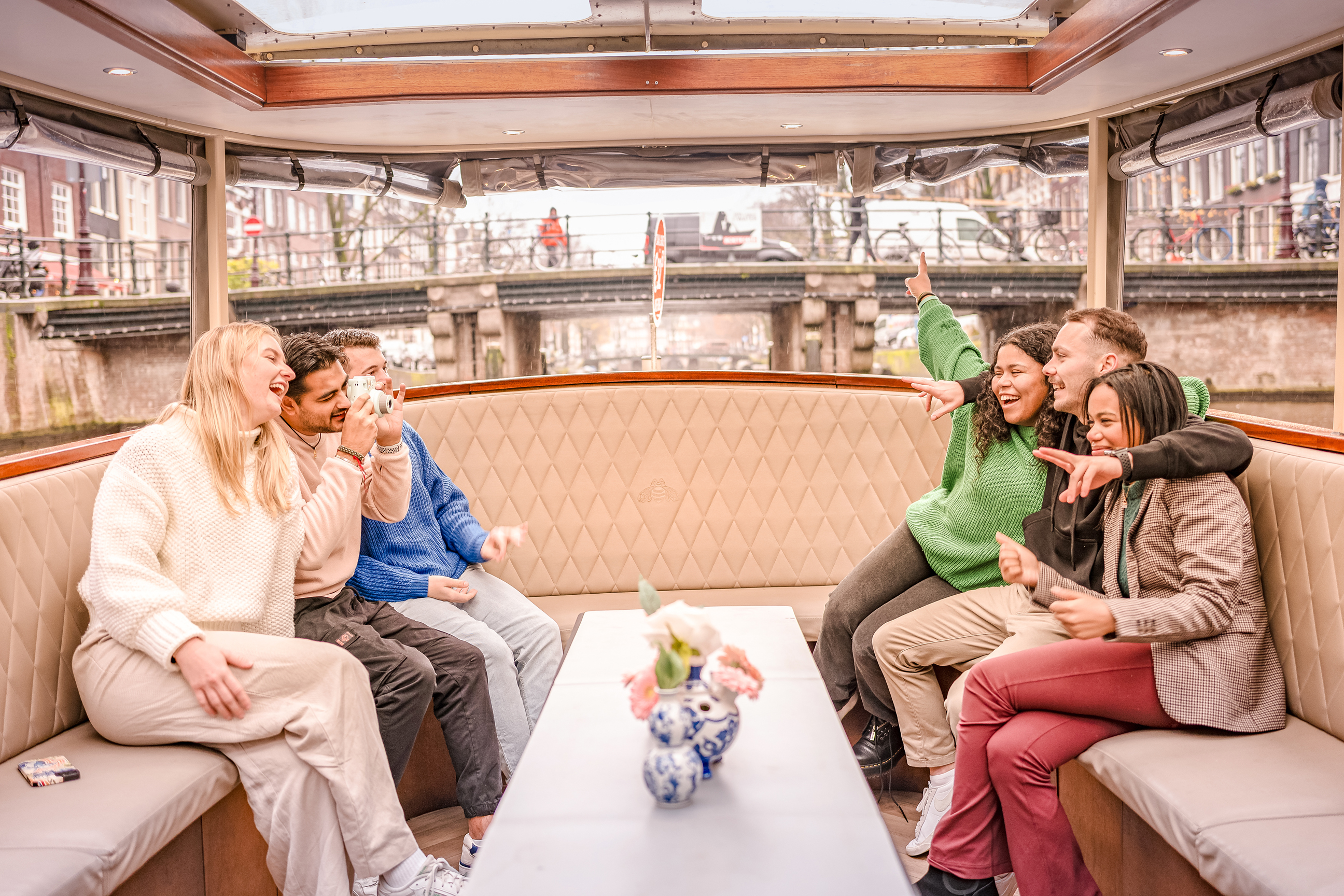 Travellers enjoying a drink together on the Evening Canal Cruise in Amsterdam, Netherlands
