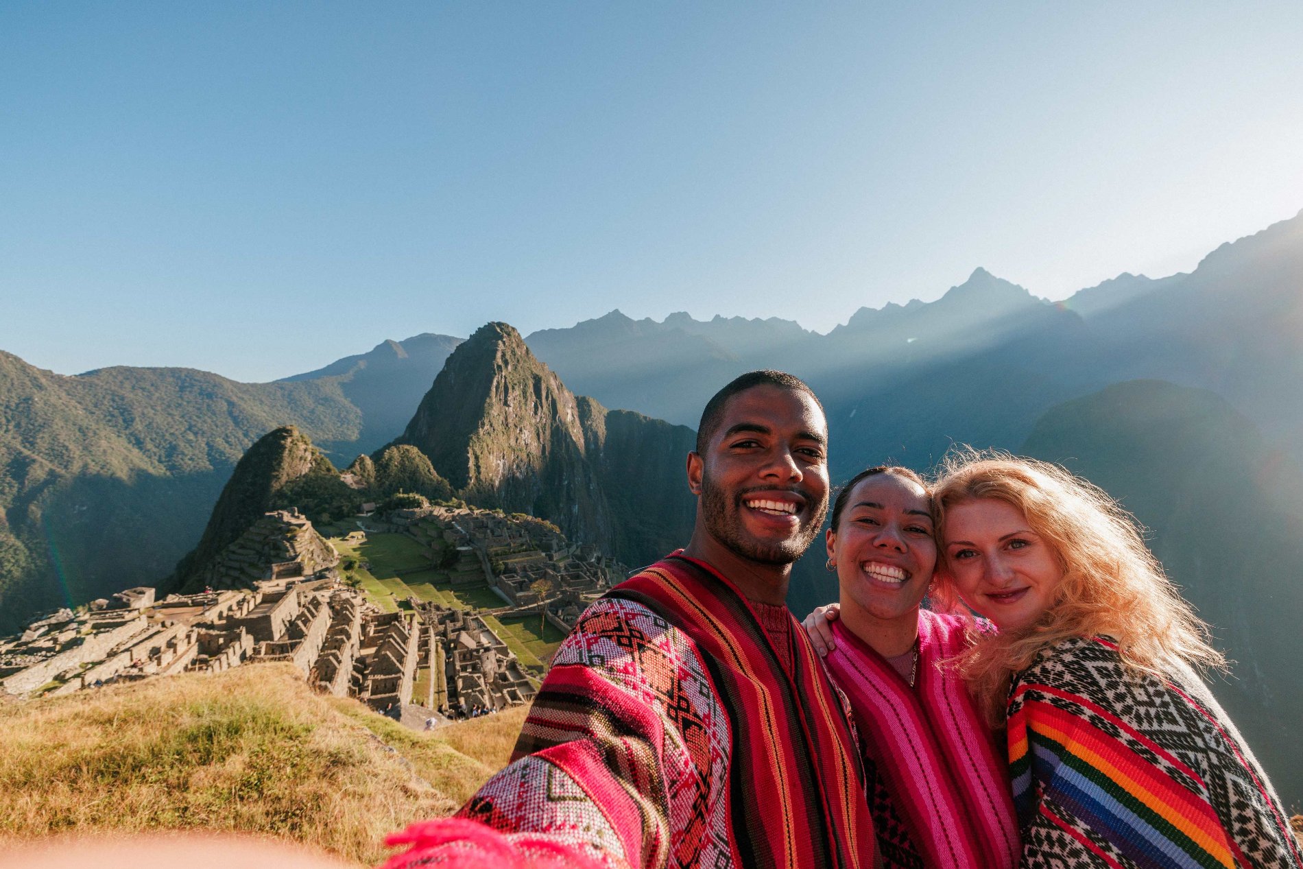 Three people taking a selfie with a landmark as background in Peru
