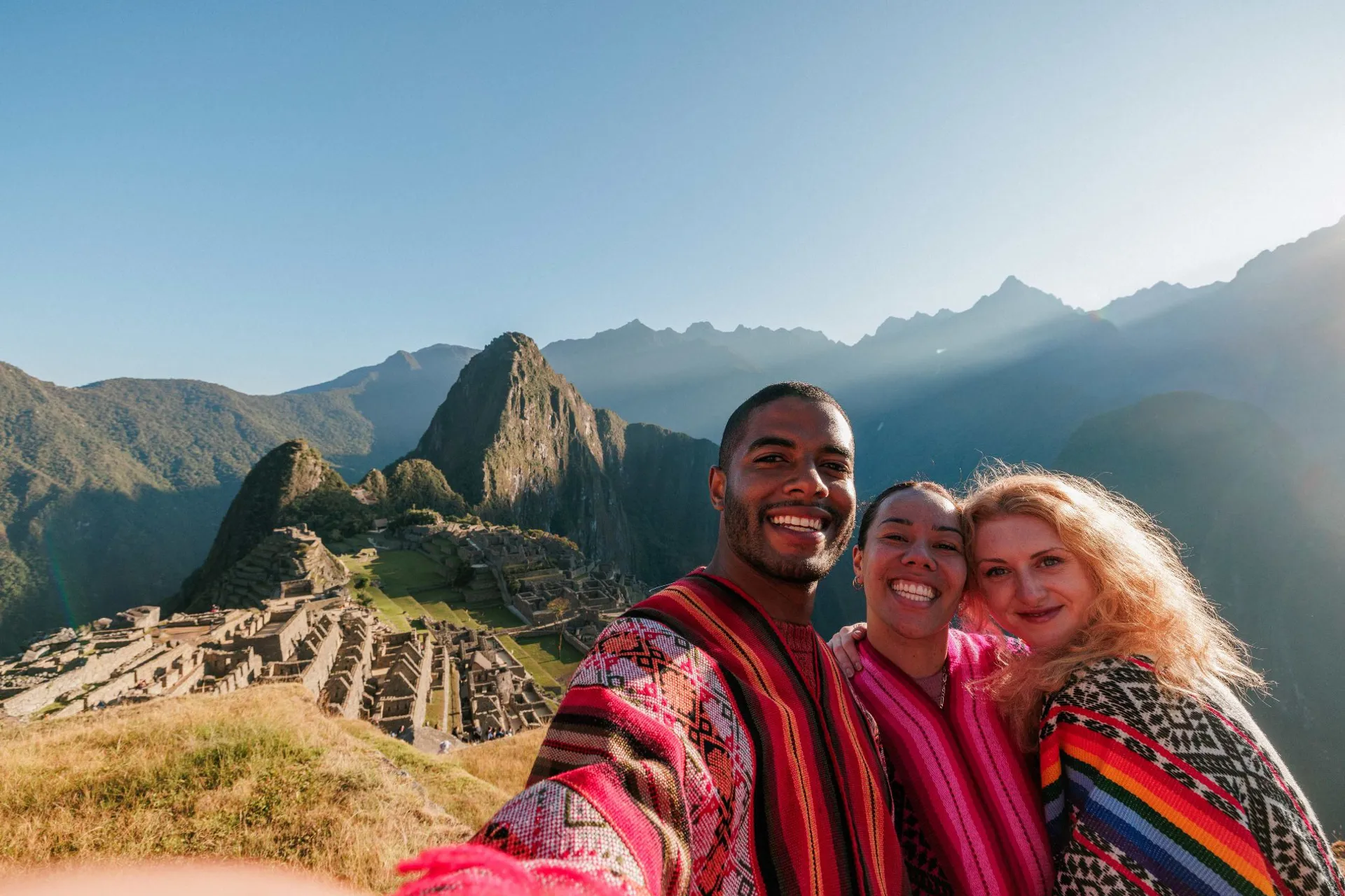 Three people taking a selfie with a landmark as background in Peru