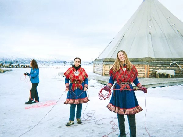 Two women in the snow wearing traditional Norway clothes.