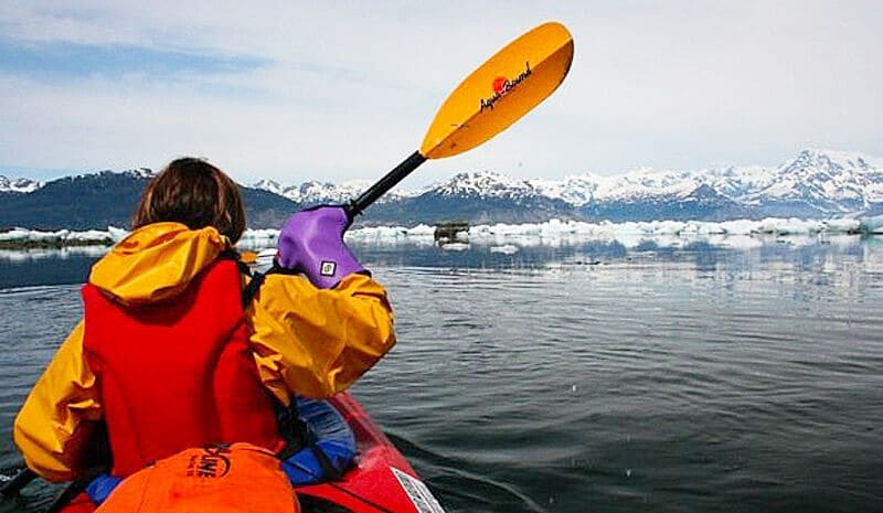  A girl canoeing on a lake surrounded by a winter landscape