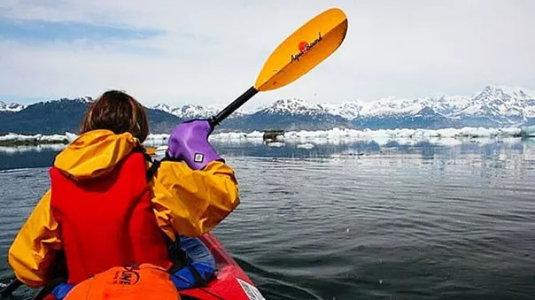 A girl canoeing on a lake surrounded by a winter landscape