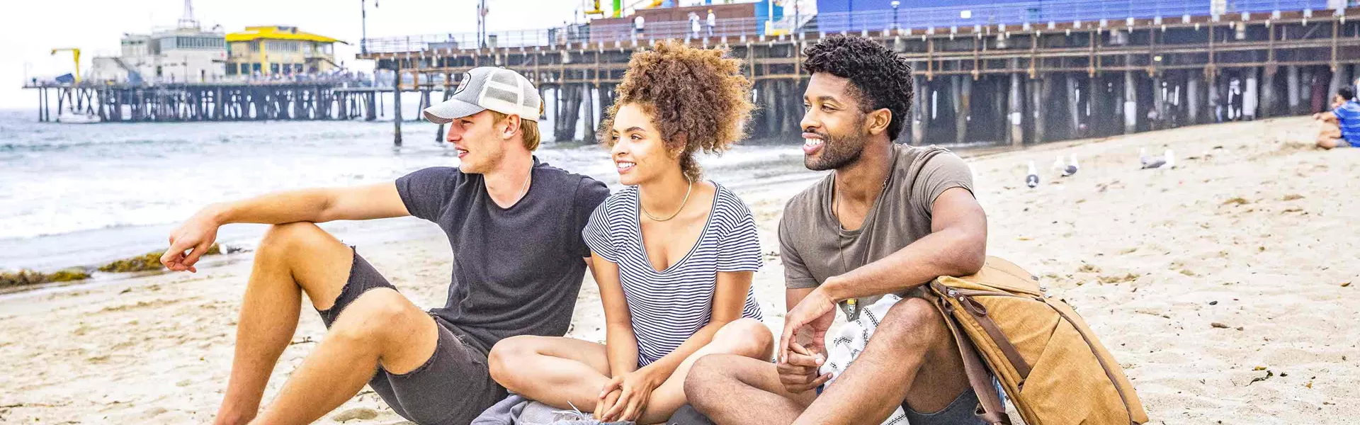 Trio Of Young Travelers Sitting On La Beach Usa 0189AMER2018