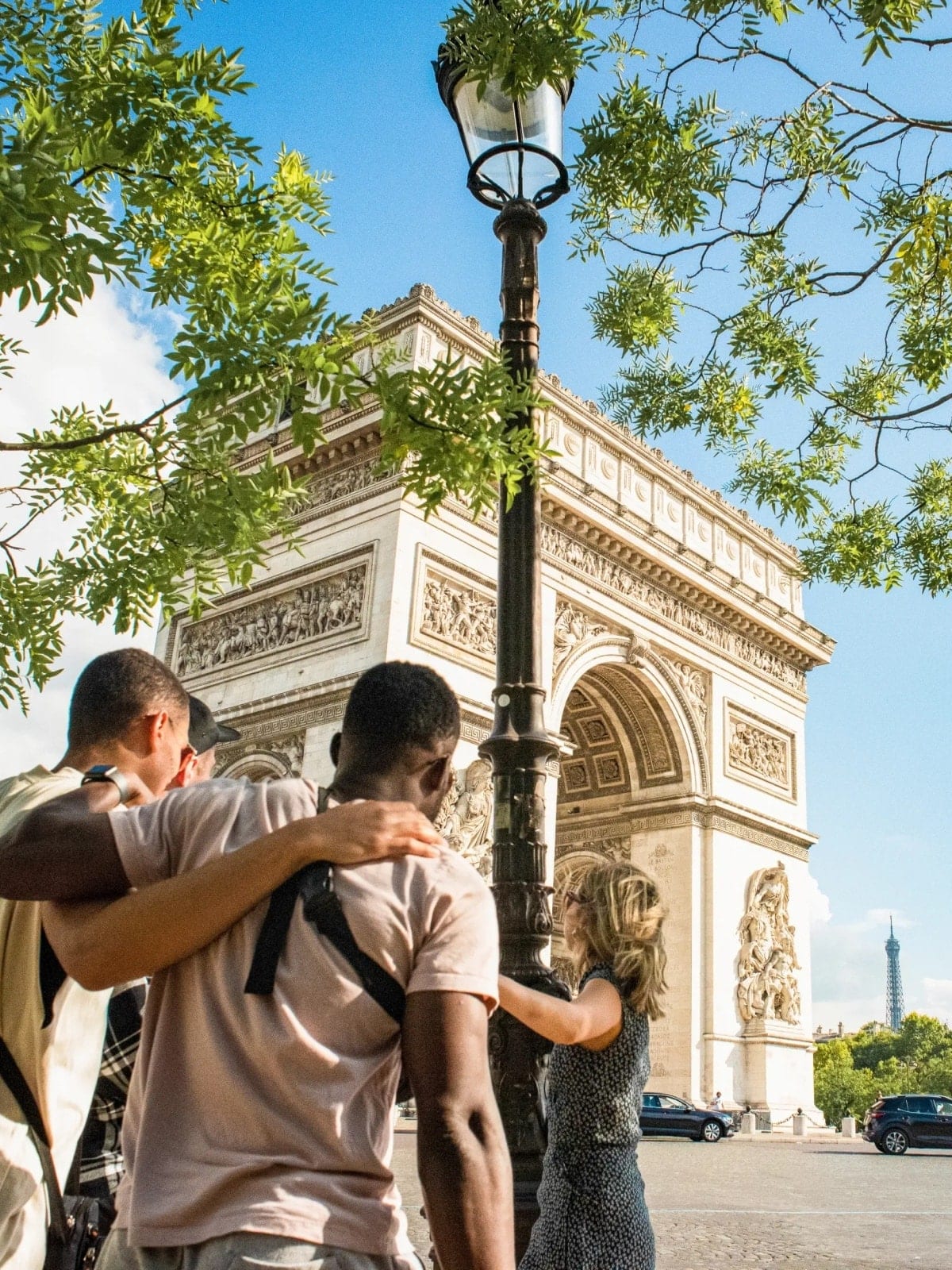 Friends standing together in front of the Arc de Triomphe in Paris, France.