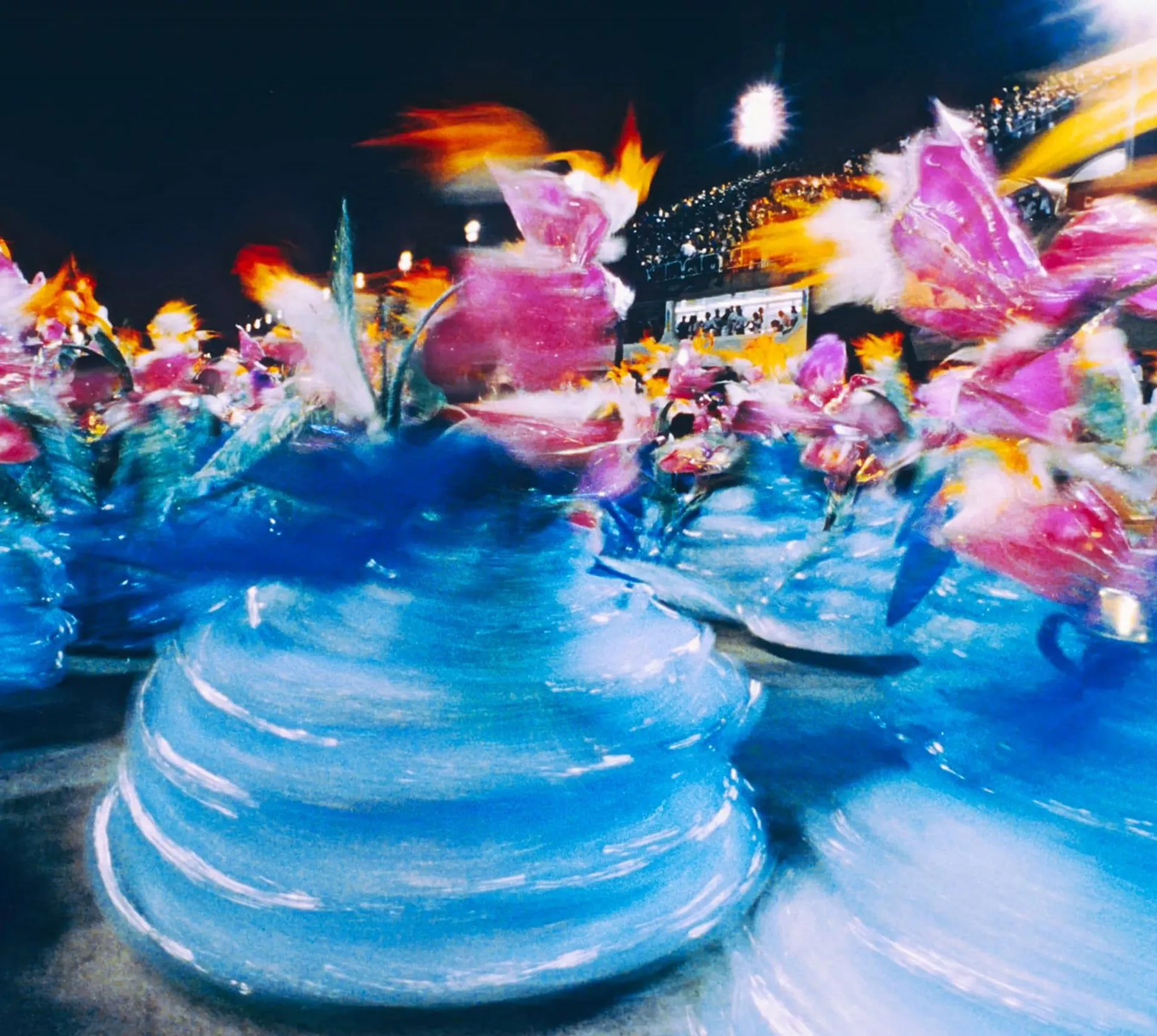 Motion-blurred samba dancers in vibrant blue and pink carnival costumes at the Sambadrome Rio Carnival Brazil - Contiki Brazil Tour