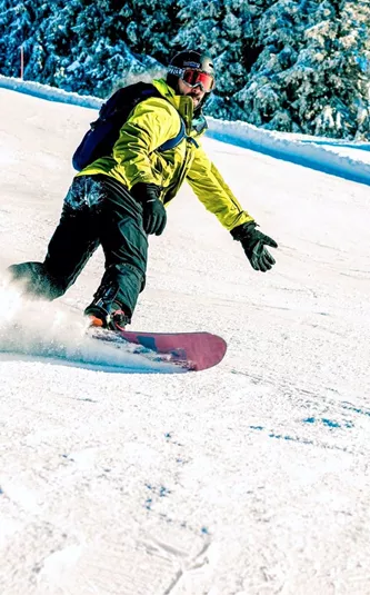 A snowboarder carves down a snowy slope in the Austrian Alps, with skiers following behind on a clear winter day