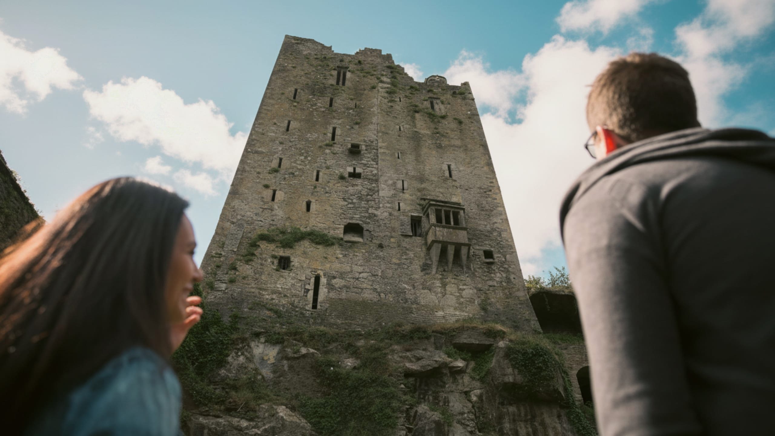 Two people look up at the historic Blarney Castle in County Cork - Contiki Ireland in a Week Tour