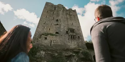 Two people look up at the historic Blarney Castle in County Cork - Contiki Ireland in a Week Tour