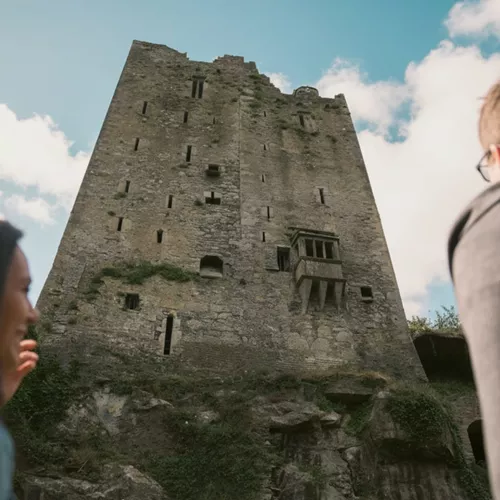 Two people look up at the historic Blarney Castle in County Cork - Contiki Ireland in a Week Tour