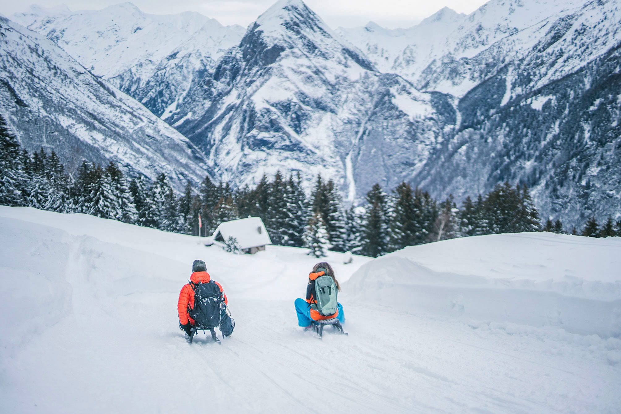 Two travellers sledding down a snowy mountain in the Swiss Alps