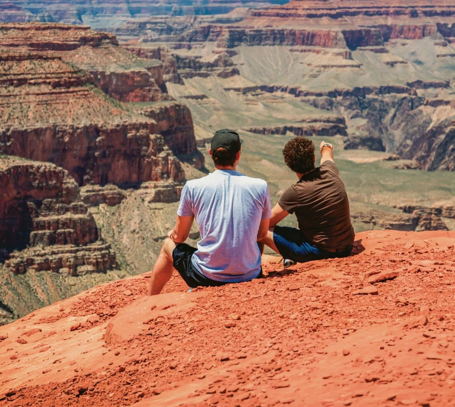 Two Contiki travellers overlooking the Grand Canyon National Park, taking in panoramic views of the iconic red rock cliffs on the Los Angeles to Dallas Tour