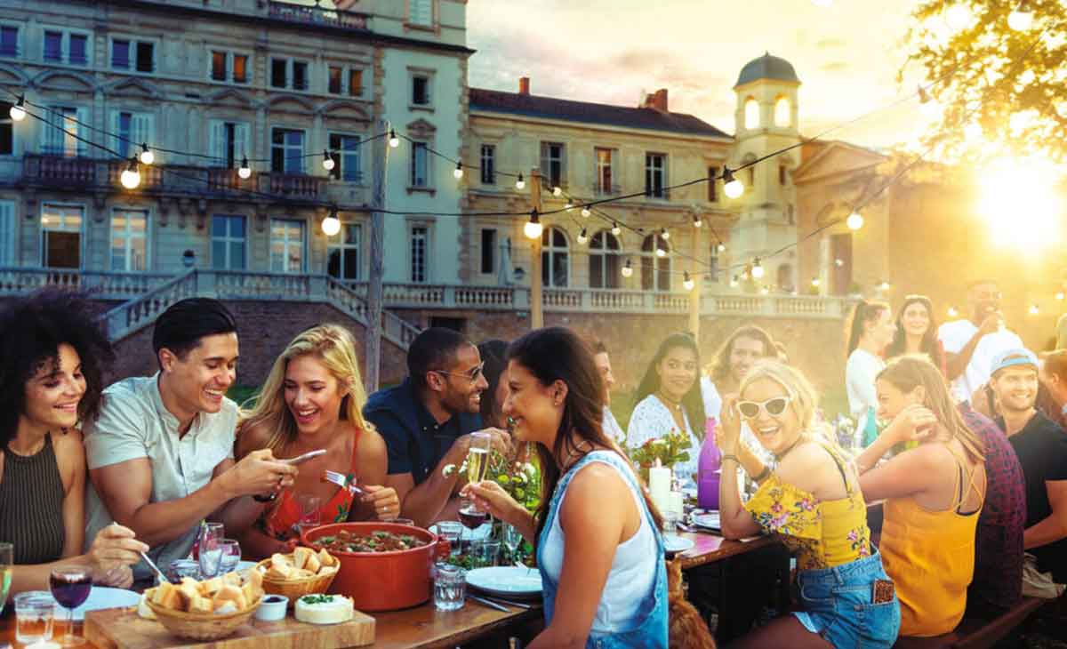 Group Of Travelers Eating Al Fresco At Chateau In France