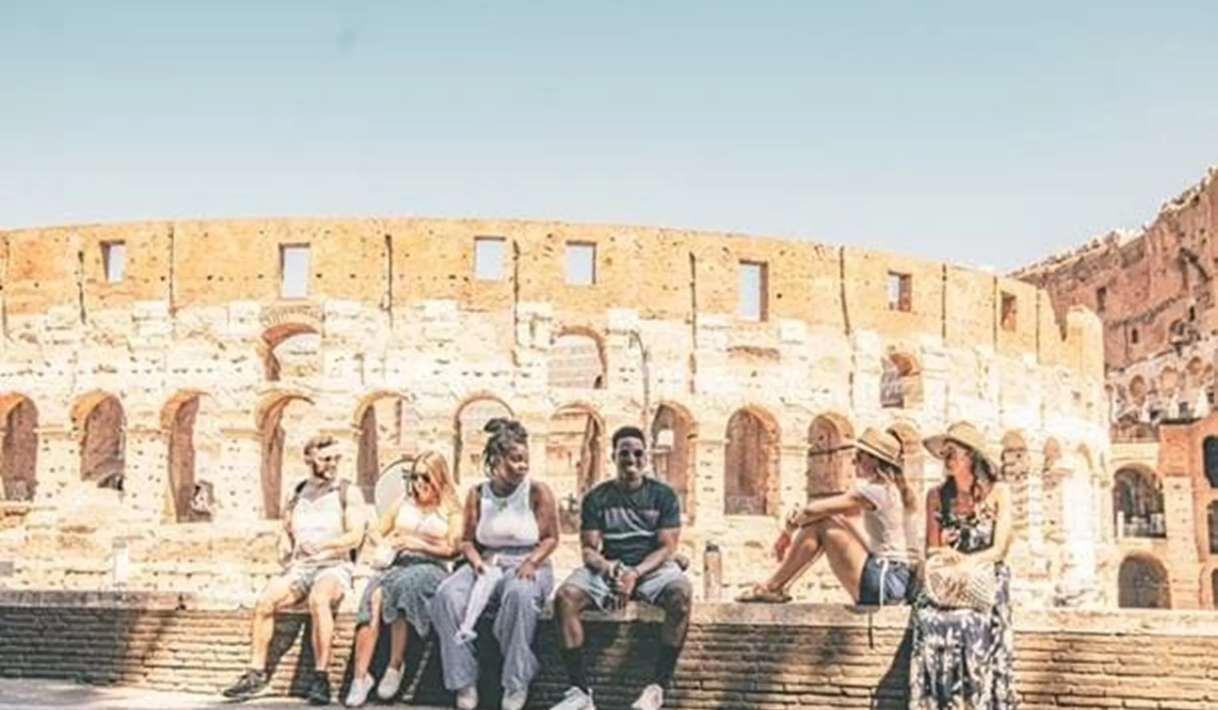 Group of young people sitting on stairs in front of Coloseum in Rome, Italy