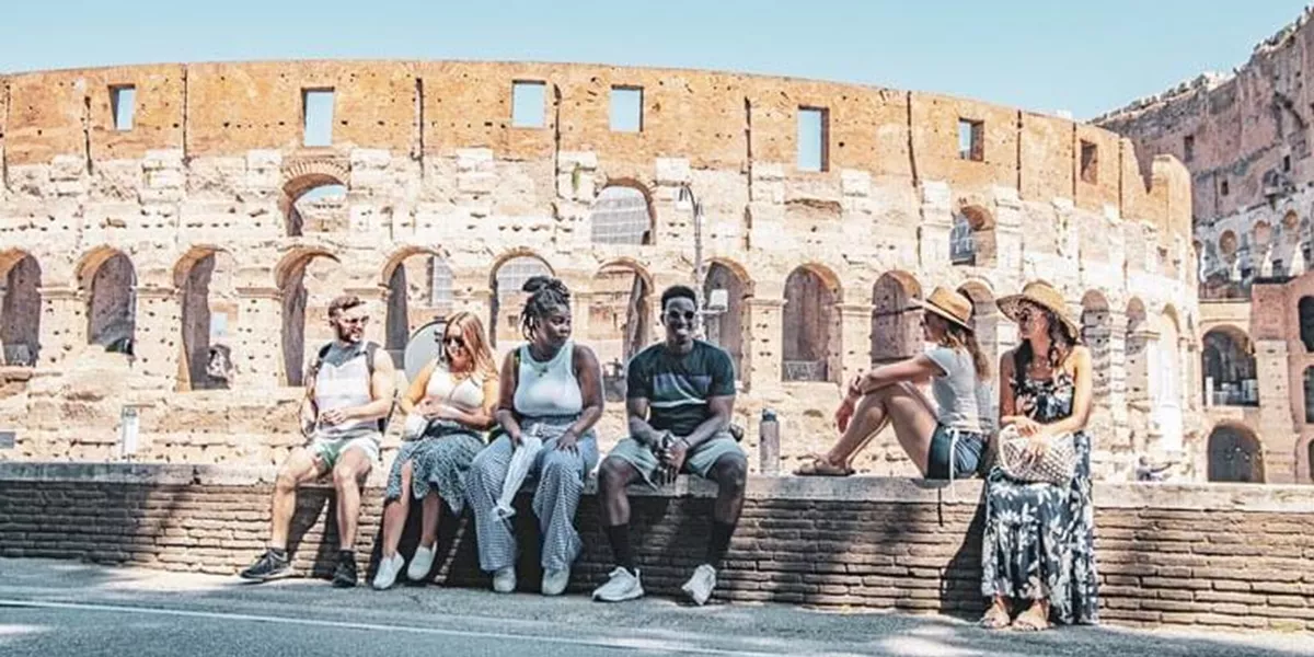 Travellers sitting on a wall in front of Colloseum in Rome