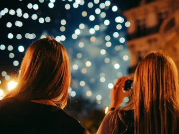 Two young women photographing New Year's Eve fireworks display in Paris France at night - Contiki Paris New Year's Eve Tour