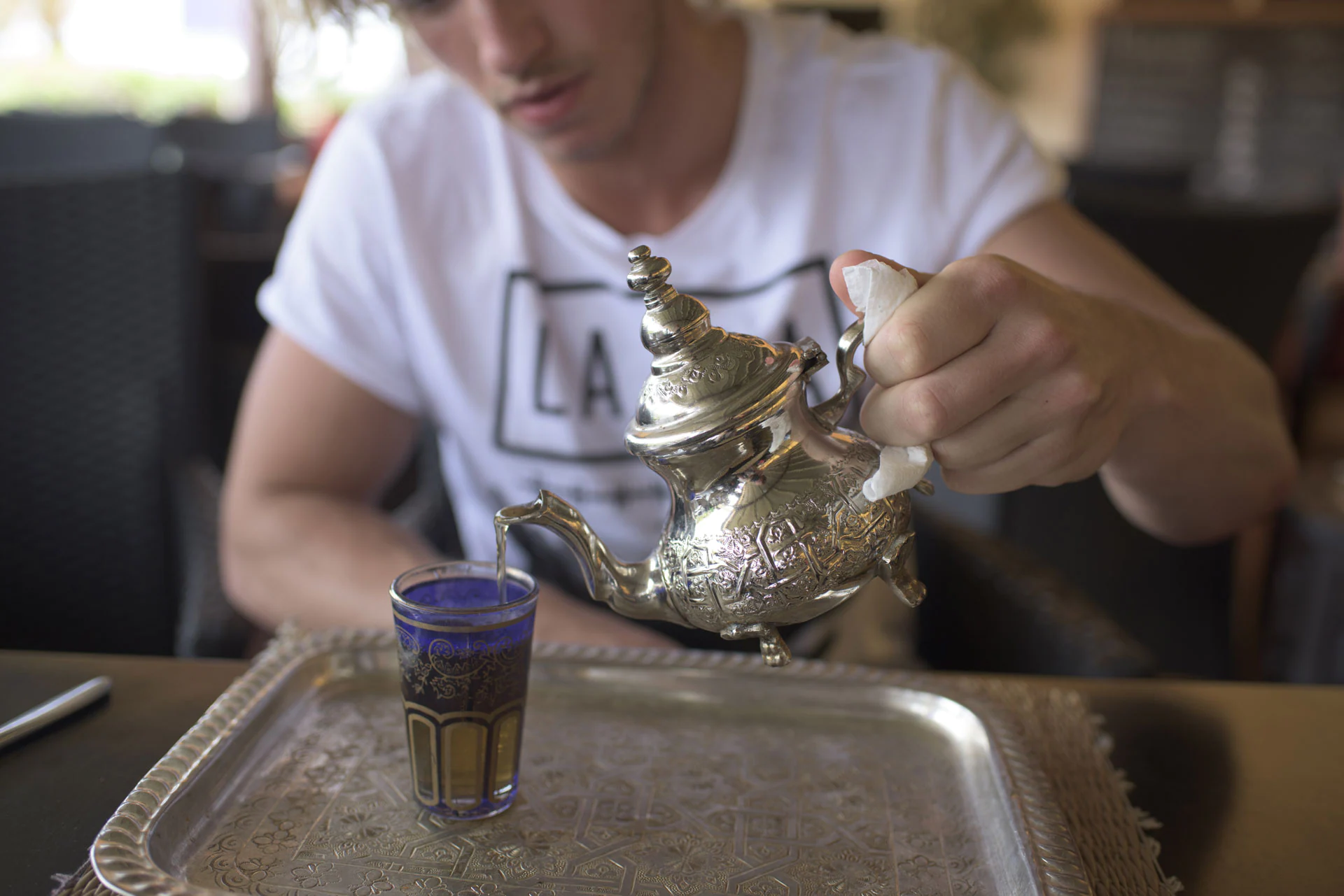 Man pouring tea from silver tea pot