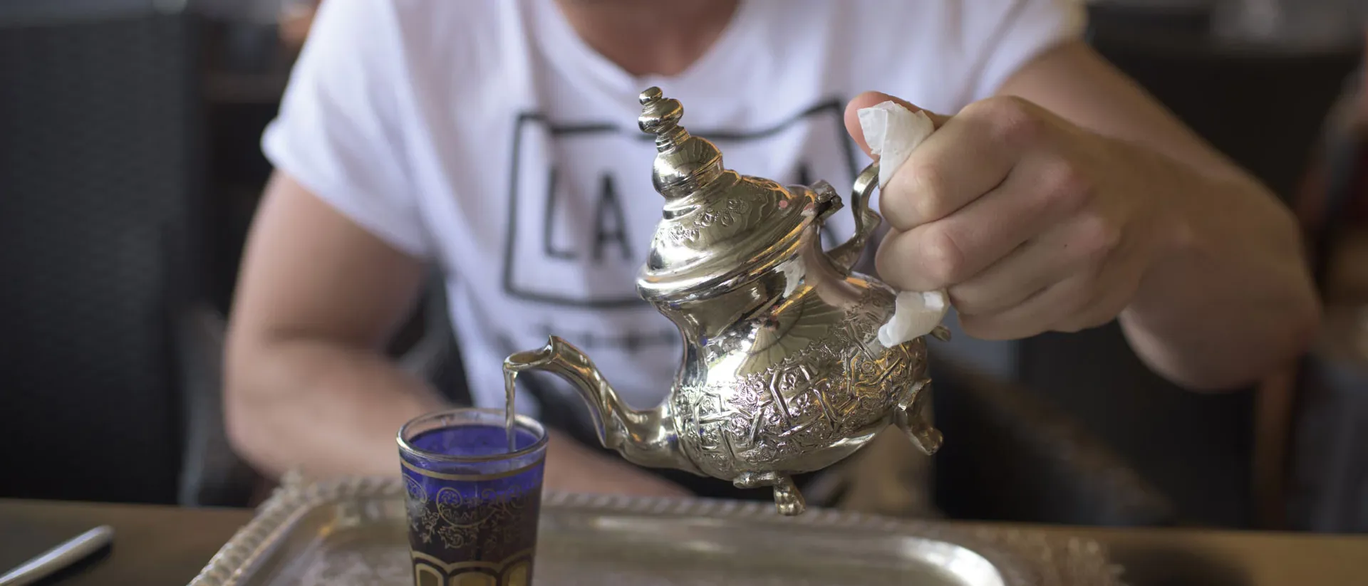 Man pouring tea from silver tea pot