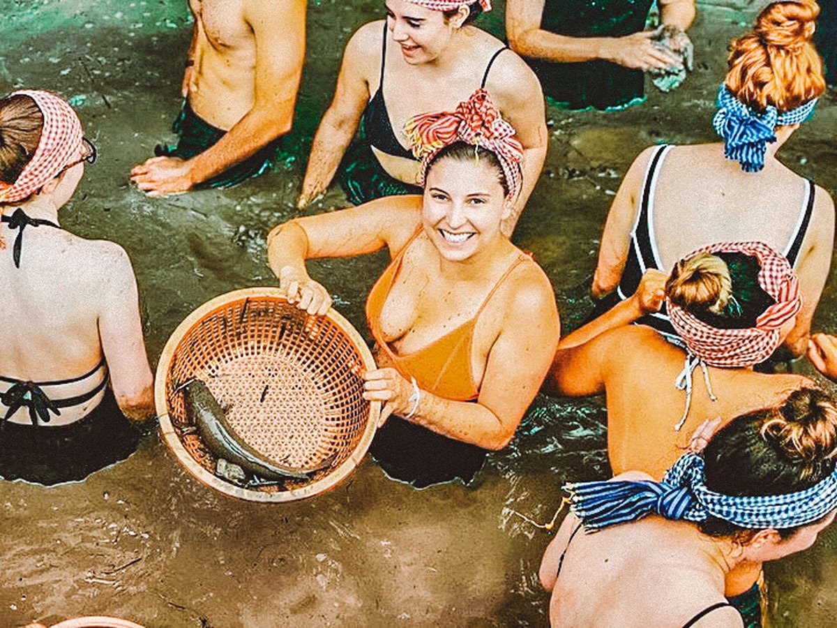 People In A River Woman Holding Basket With A Fish In It in Vietnam..