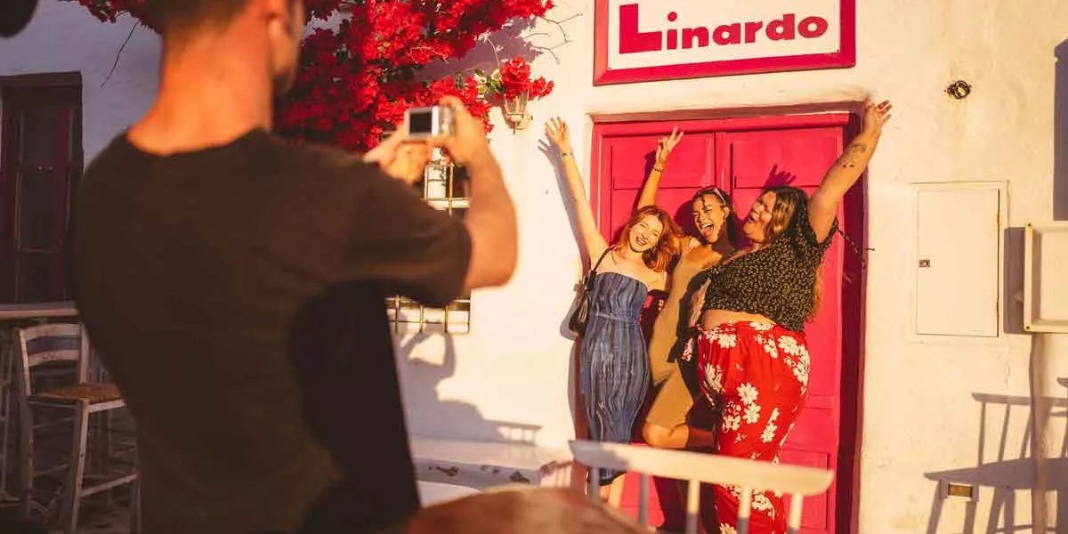 Happy Friends Taking A Picture In Front Of Bright Pink Door