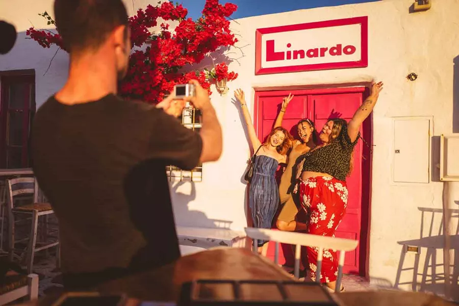 Happy Friends Taking A Picture In Front Of Bright Pink Door