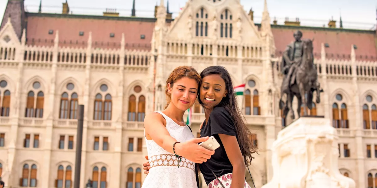 Travellers taking a photo in front of the parliament building in Budapest, Hungary