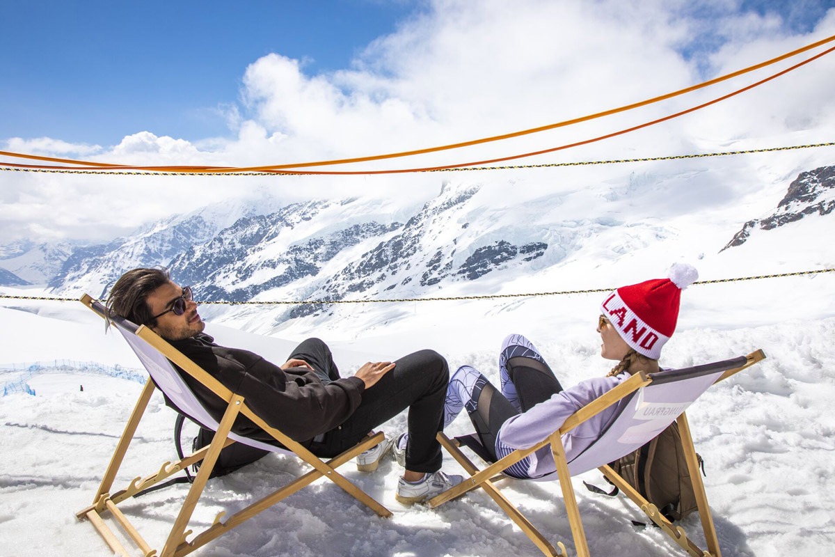 Friends Sittign And Relaxing While Looking At Snowy Mountain in Switzerland.