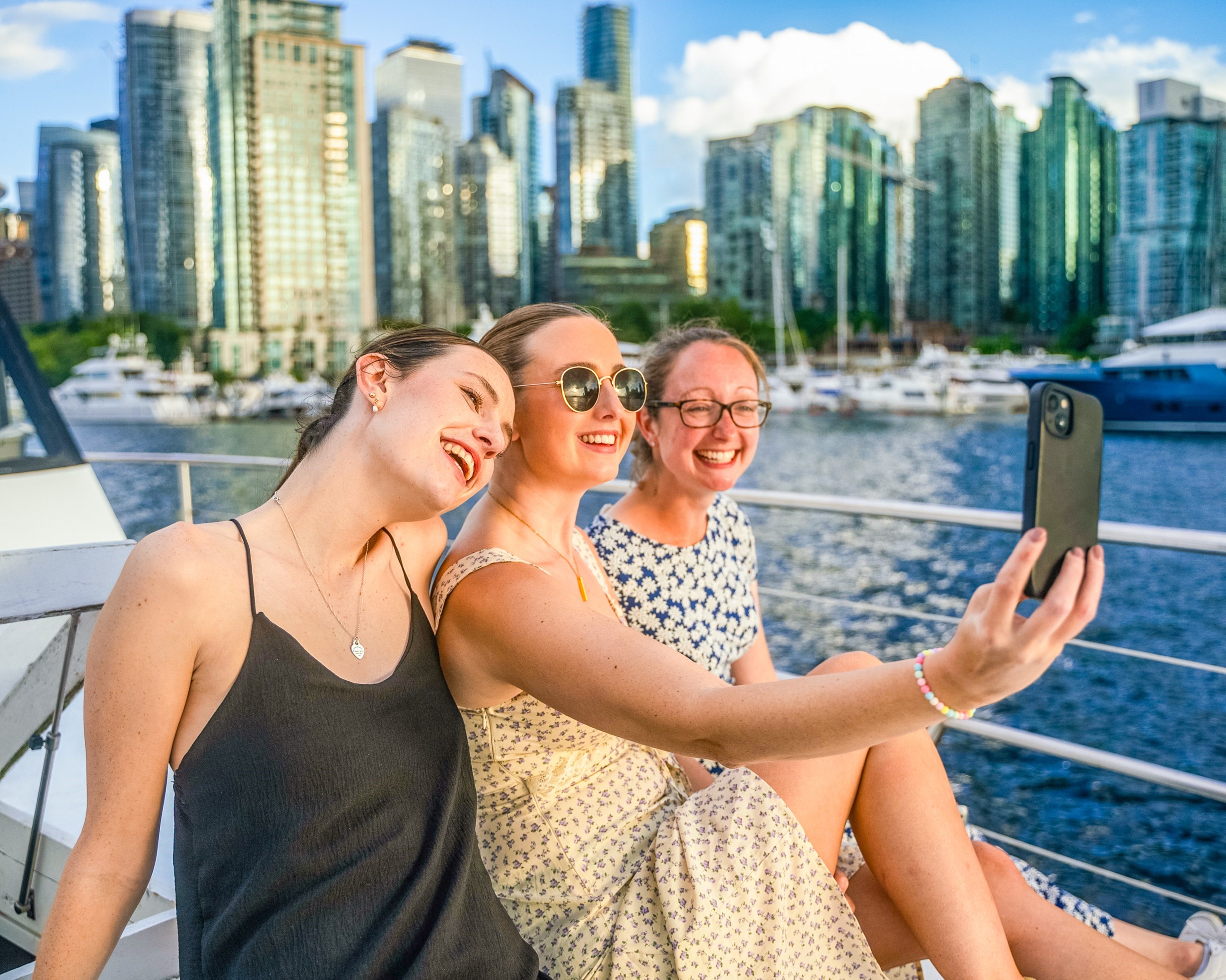 Travellers Taking a Selfie Together on Boat Cruise around Vancouver with Skyline in Background, Canada