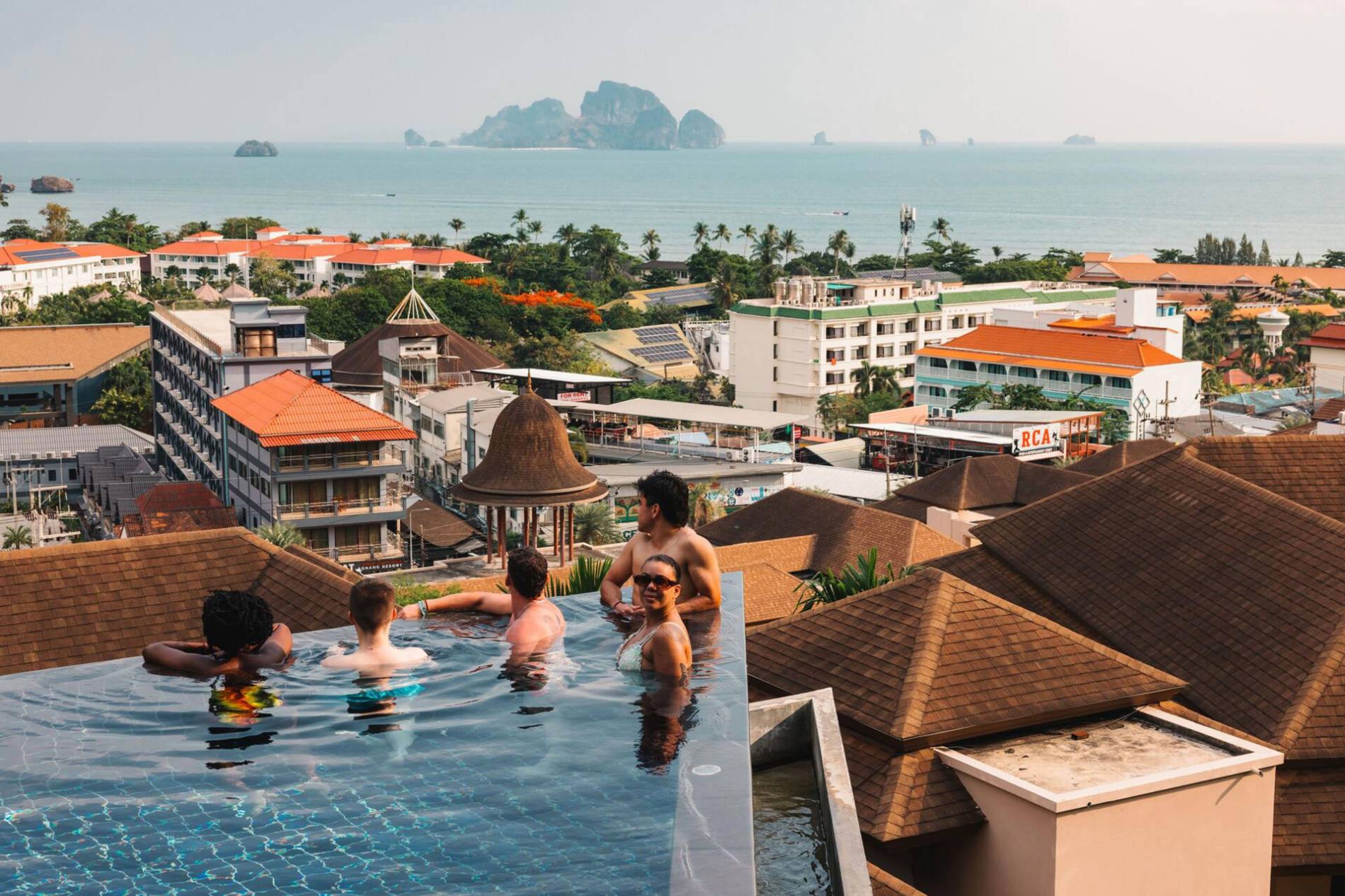 People swimming rooftop with city and sea view