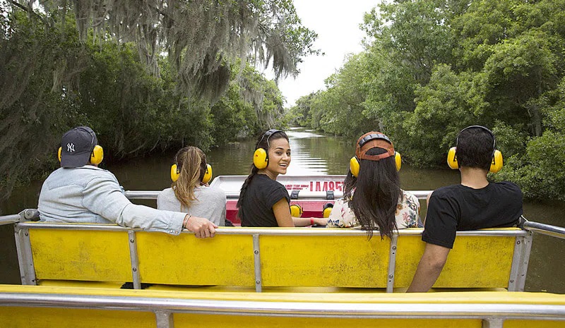 People in yellow headphones are running down the river among lush vegetation