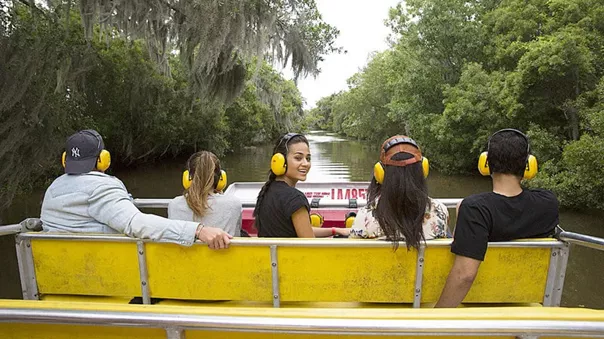 People in yellow headphones are running down the river among lush vegetation