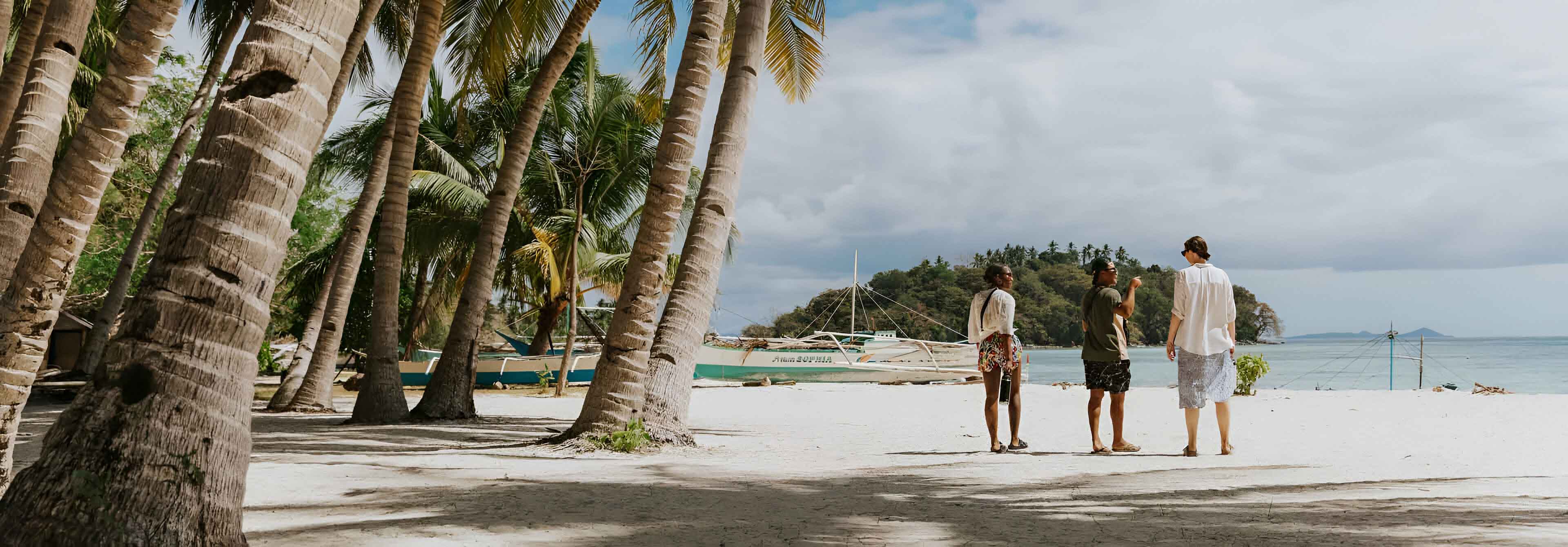 Three People Talking While Walking On The Beach in Philippines.