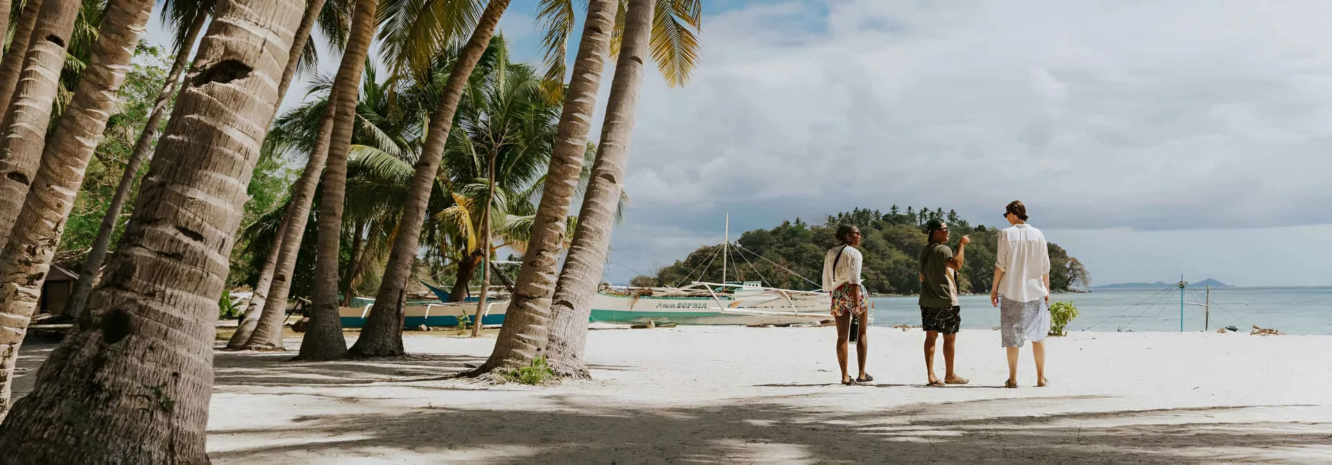Three People Talking While Walking On The Beach in Philippines.