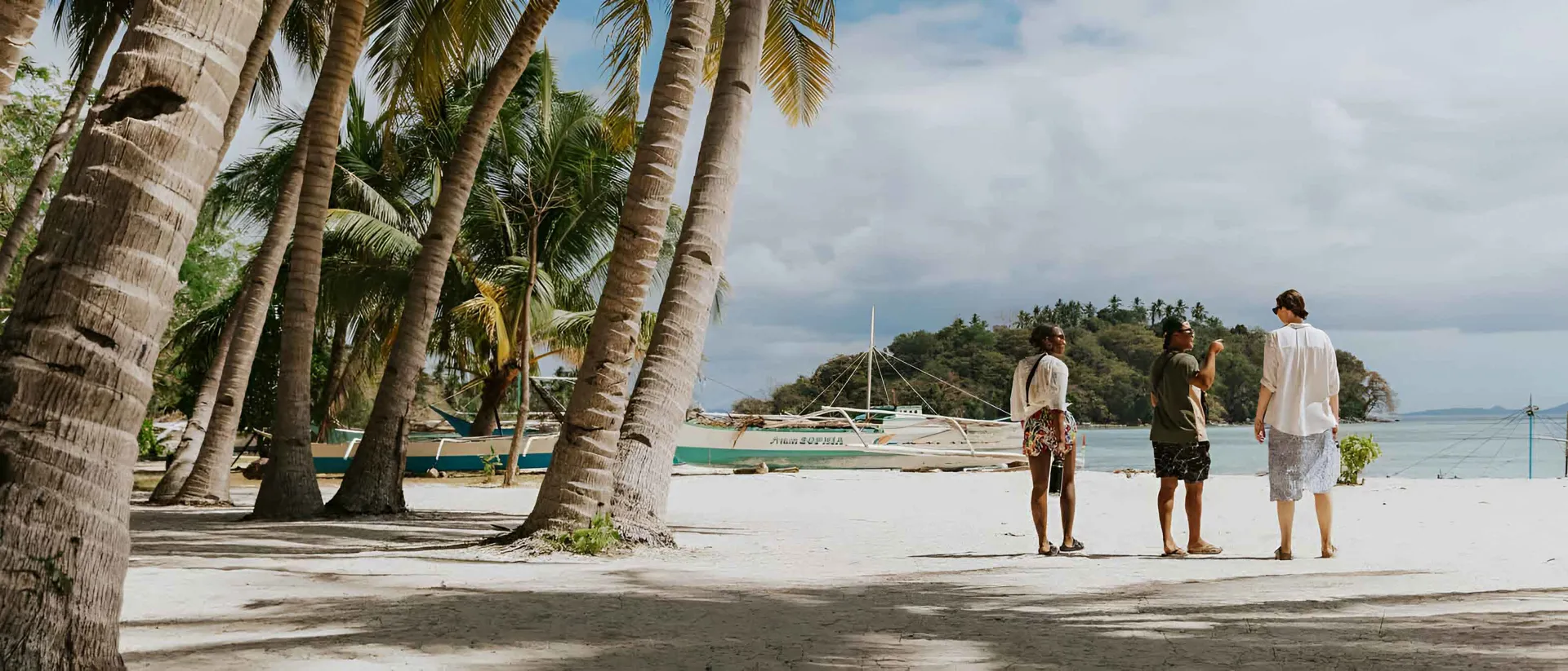 Three People Talking While Walking On The Beach in Philippines.