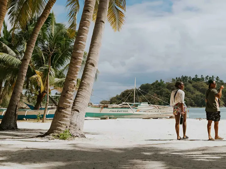 Three People Talking While Walking On The Beach in Philippines.