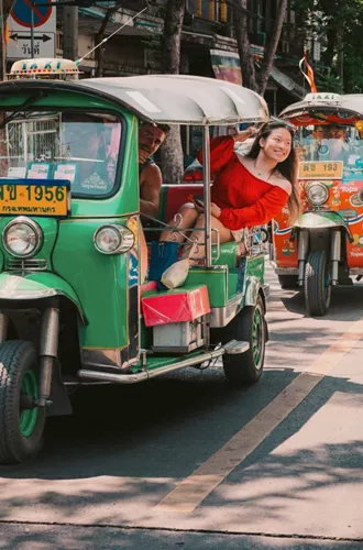 Travellers ride colourful tuk-tuks through the streets of Bangkok on the Contiki Best of Thailand Tour