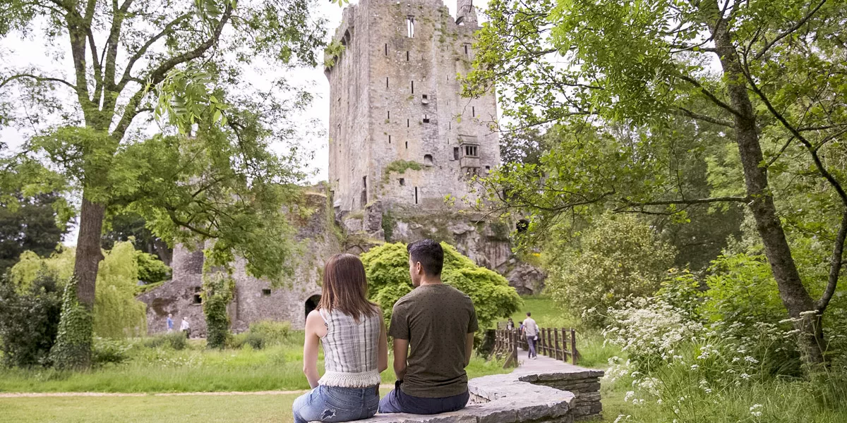 Couple Sitting Looking At Castle And Gardens