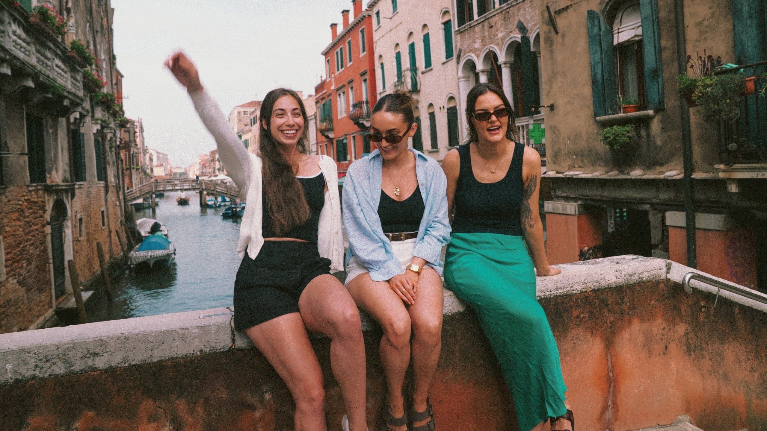 Contiki travellers relaxing on a bridge overlooking a canal in Venice, Italy, on the Vienna to Rome Trail Tour