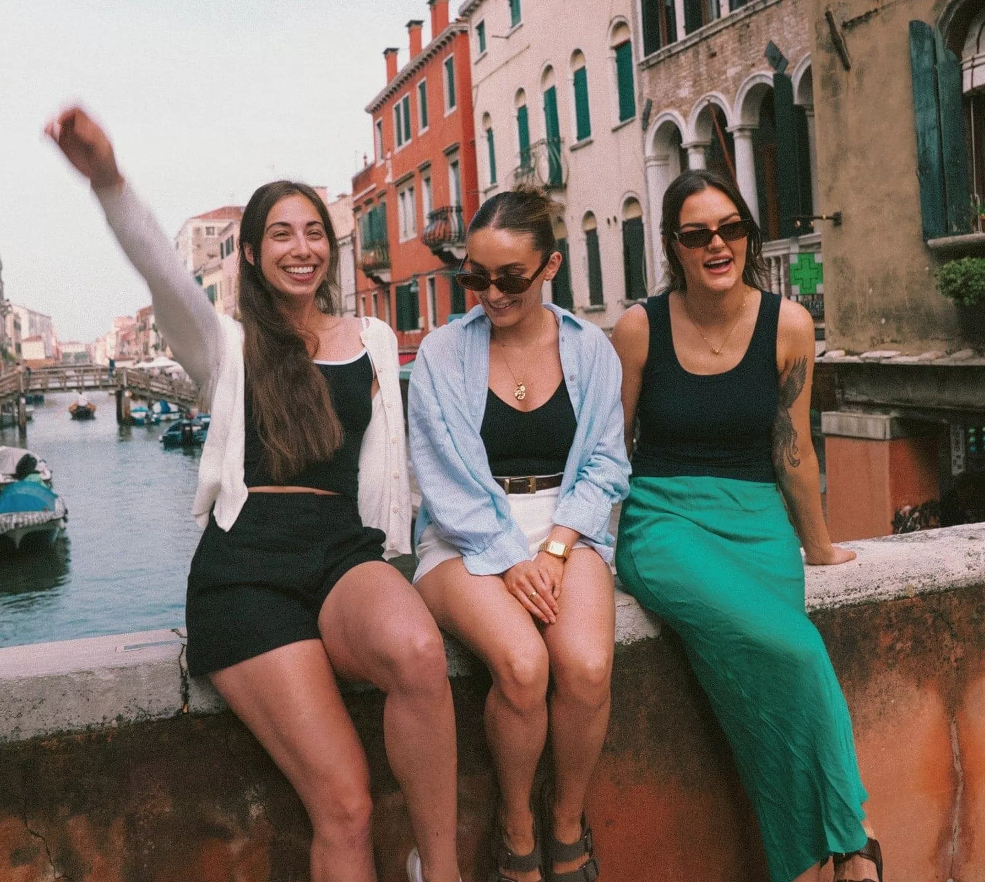 Contiki travellers relaxing on a bridge overlooking a canal in Venice, Italy, on the Vienna to Rome Trail Tour