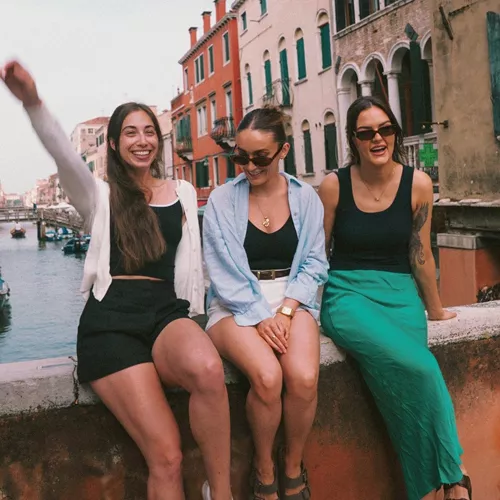 Contiki travellers relaxing on a bridge overlooking a canal in Venice, Italy, on the Vienna to Rome Trail Tour