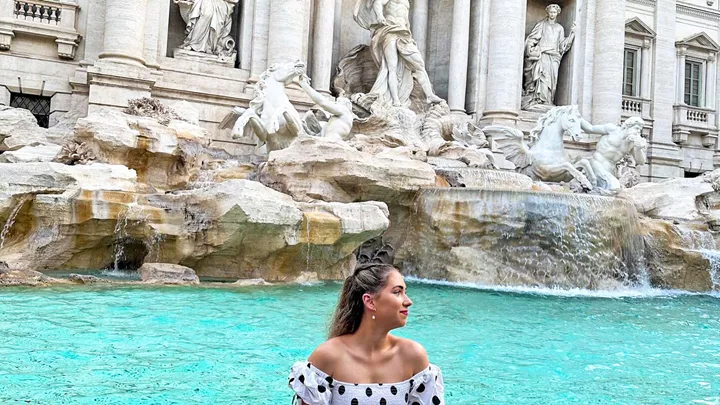 Traveller sitting on the edge of the Trevi Fountain in Rome, Italy