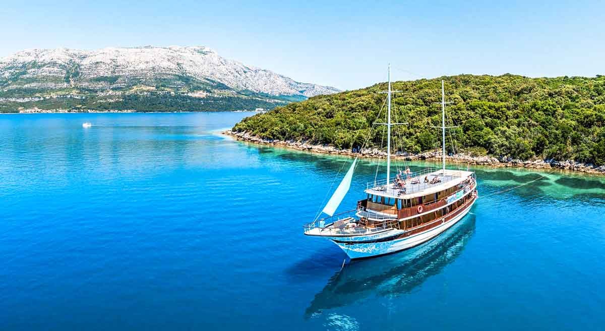 Sailing boat on blue waters of Croatia coast with mountains in the background 
